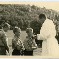 Pastoor Verstyn deelt de communie uit op kamp